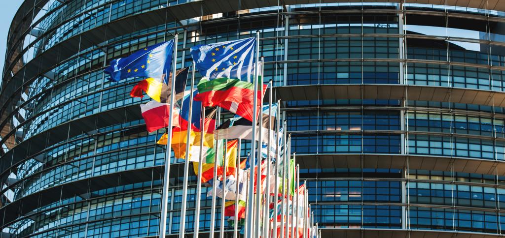 Bilde av de europeiske flaggene med Europaparlamentet i Strasbourg i bakgrunnen.