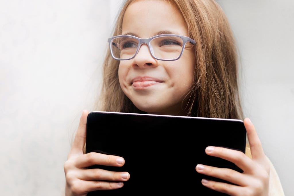 Bilde av en smilende jente med briller som holder et nettbrett